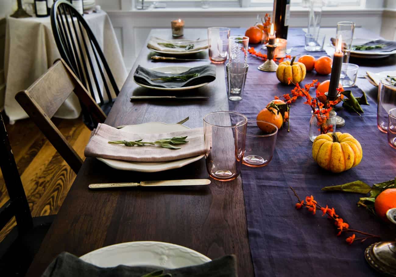 Thanksgiving tablescape with blue table runner and mini pumpkins.