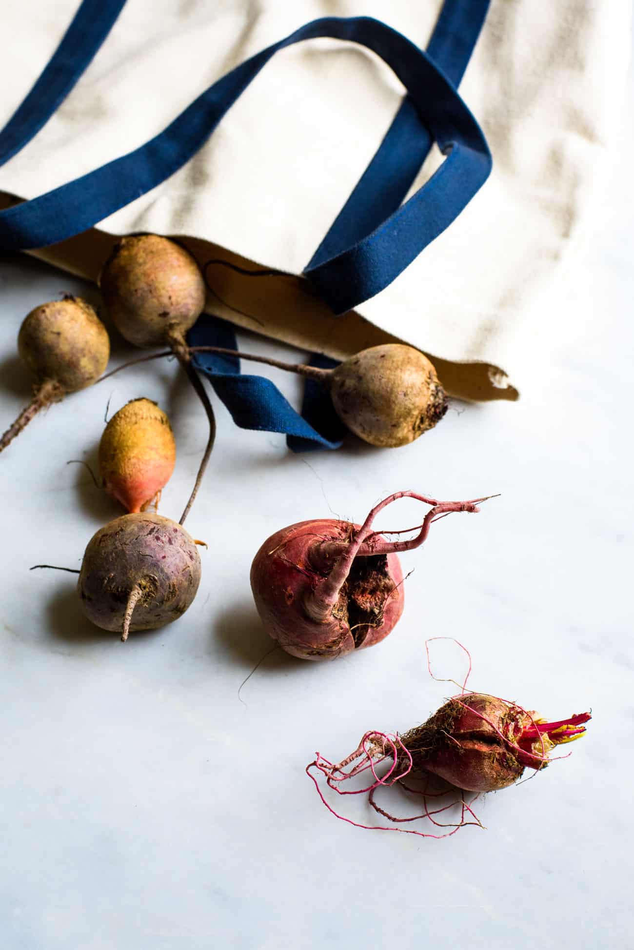 Baby rainbow beets spilling out of a farmers market bag
