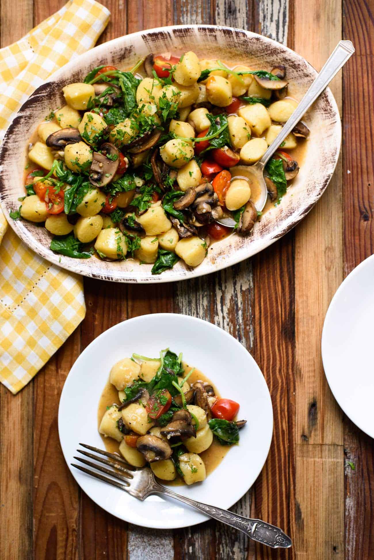 Gnocchi with mushrooms and tomatoes served on a wooden table.