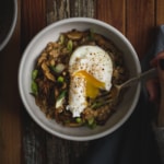 Savory farro porridge with a runny egg in a white bowl on a dark wooden background