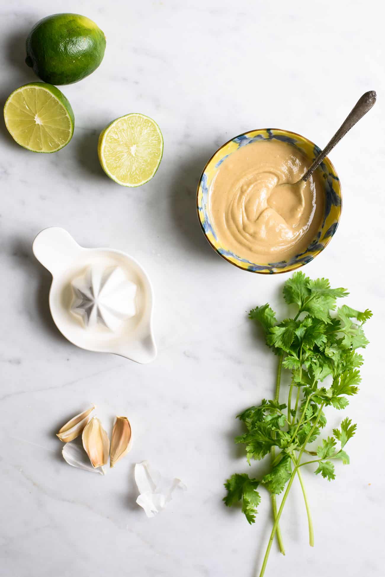 Limes, garlic, tahini and cilantro on a marble table