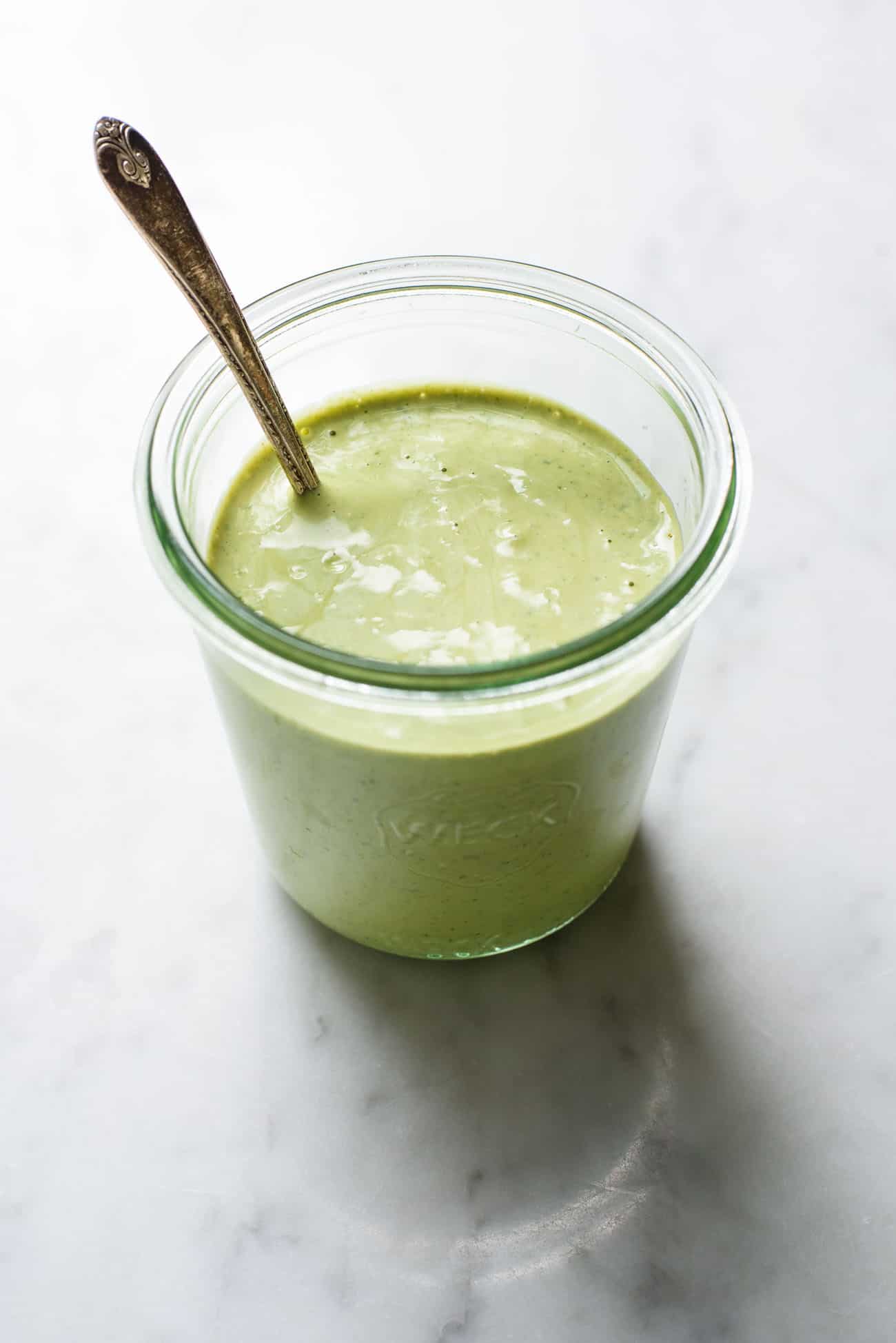 Creamy cilantro-lime tahini dressing in a Weck jar with a teaspoon.