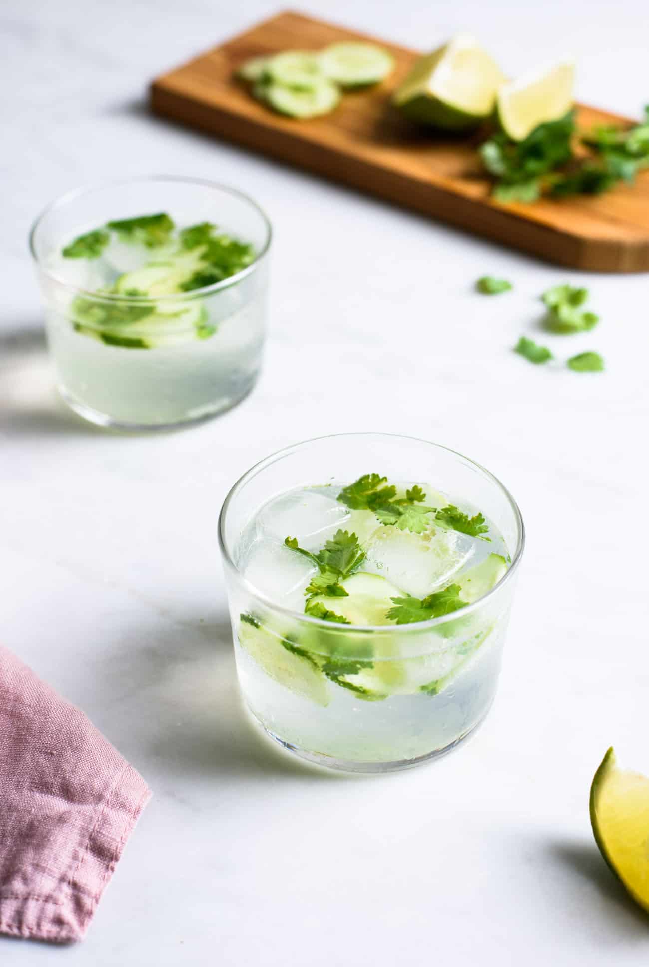 Two cilantro cucumber gin and tonics on a marble table