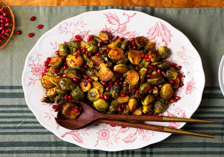 Charred Brussels sprouts in a balsamic glaze with pomegranate on a small white plate