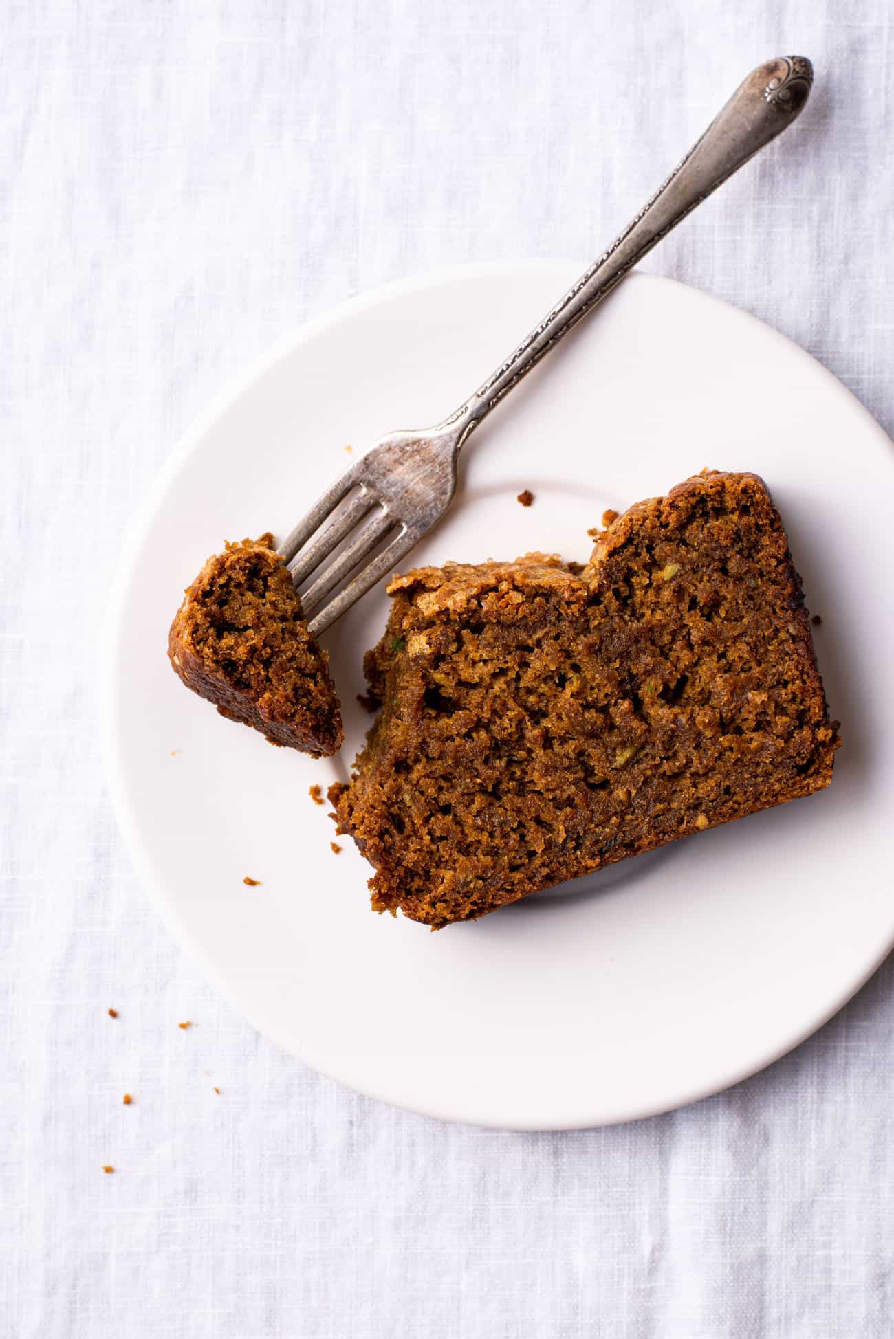 A slice of gingerbread cake on a white ceramic plate with a fork