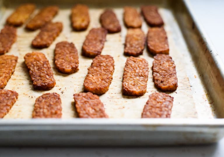 Three-quarter angle photo of tempeh bacon on a baking sheet