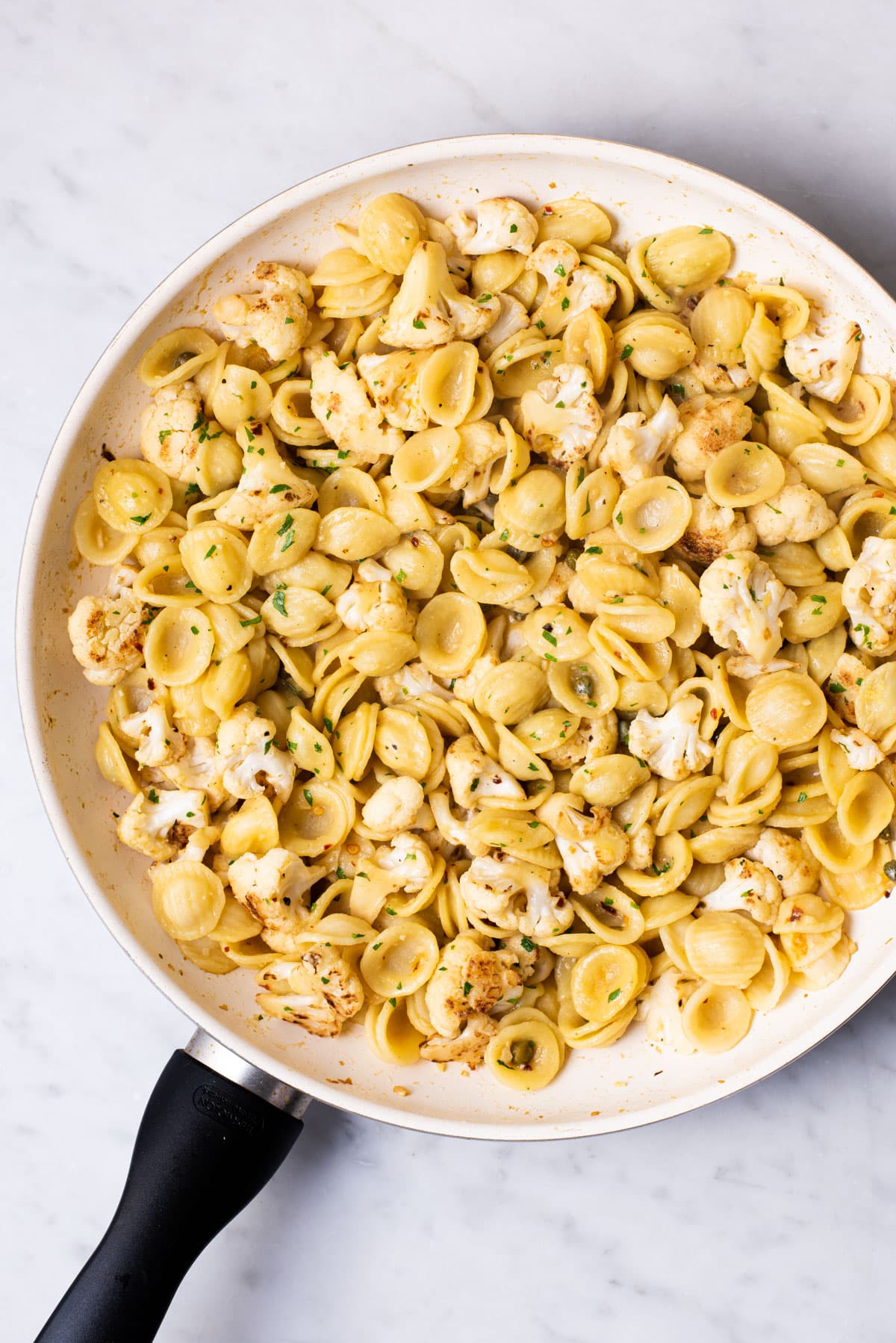 Vegan cauliflower pasta with capers and parsley in a skillet.