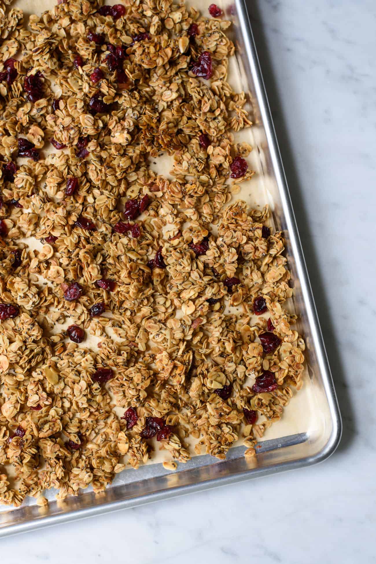 Golden brown baked granola on a baking sheet with parchment paper
