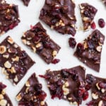 Shards of dark chocolate bark with cranberries on parchment paper