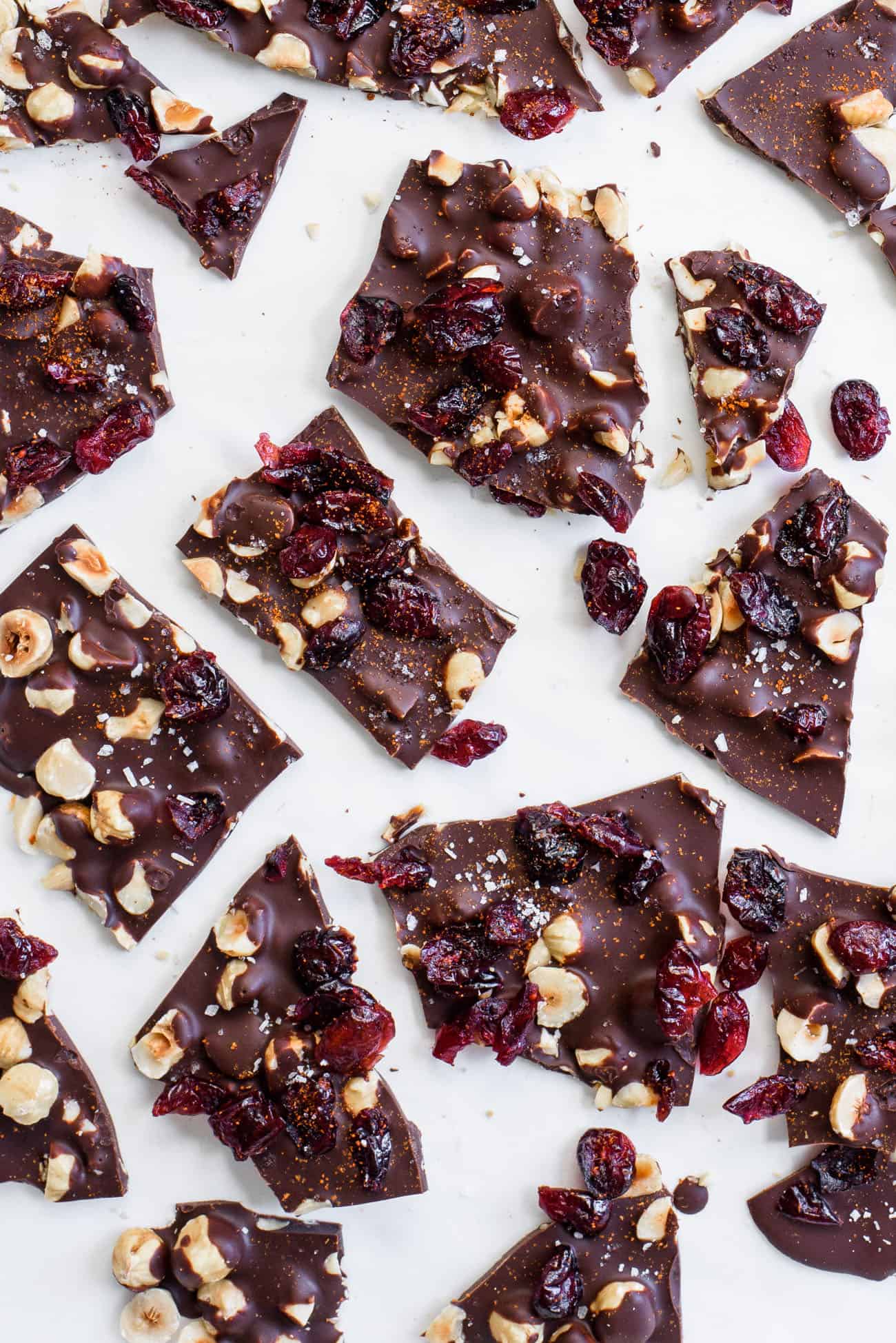 Shards of dark chocolate bark with cranberries on parchment paper