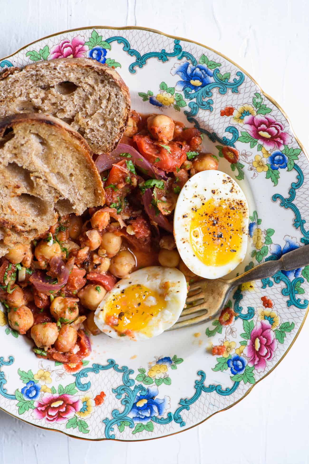 Curried chickpea breakfast hash on a colorful vintage plate with soft-boiled eggs and sourdough toast