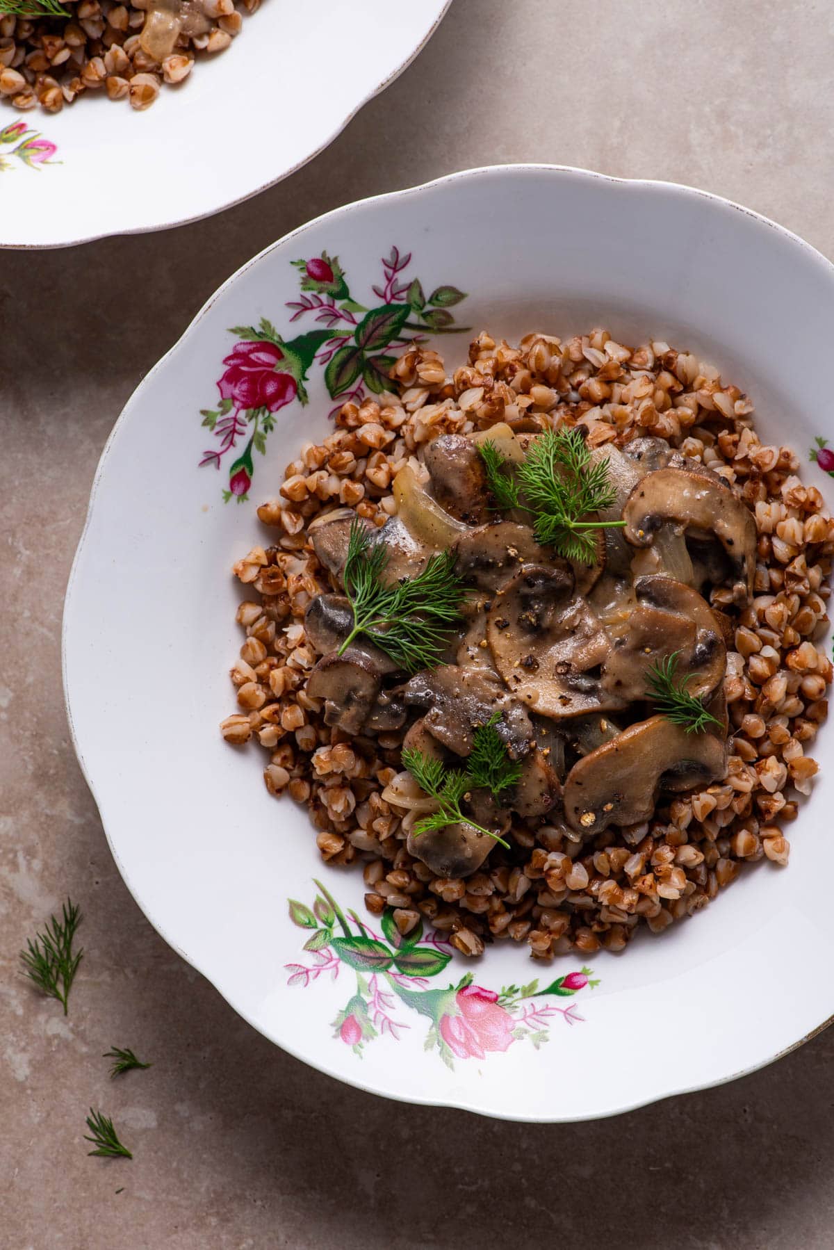 Close-up on plate of buckwheat kasha with mushrooms, onions, tahini, and dill