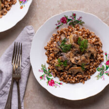 Two plates of buckwheat kasha with creamy mushrooms.