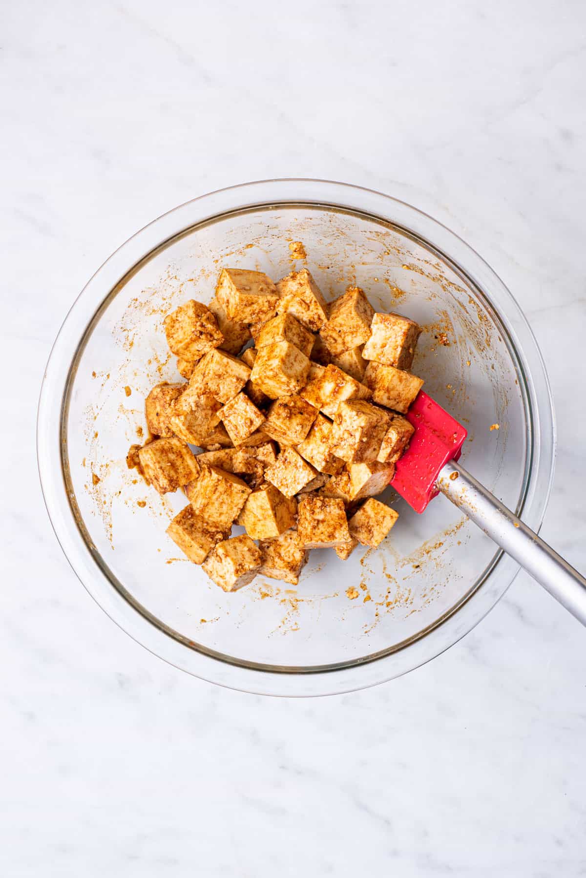 Cubes of tofu marinating in a glass bowl.