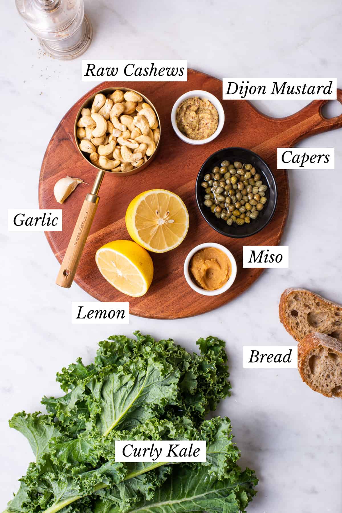 Ingredients gathered to make vegan Caesar dressing laid out on wooden board.