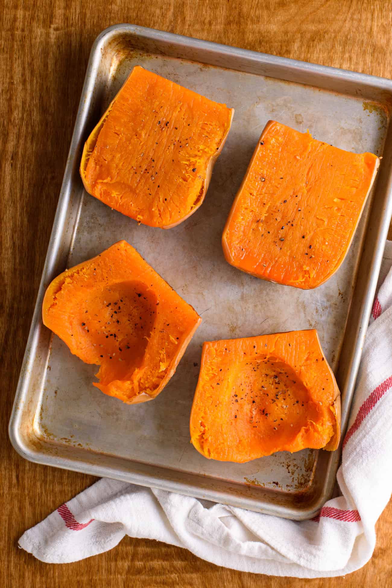 Roasted butternut squash on a baking sheet on a wooden table