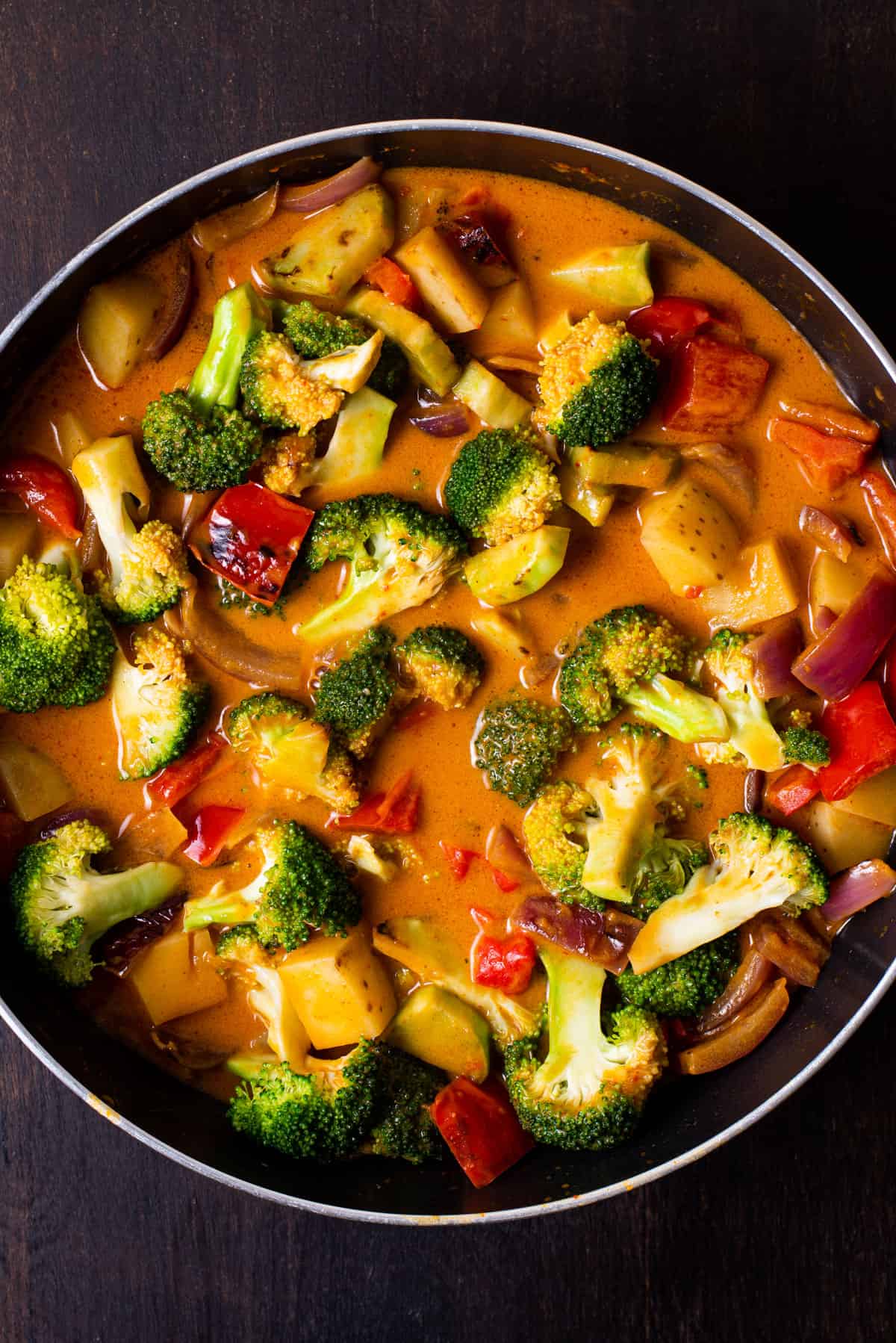 Vegan massaman curry with broccoli in a saucepan.