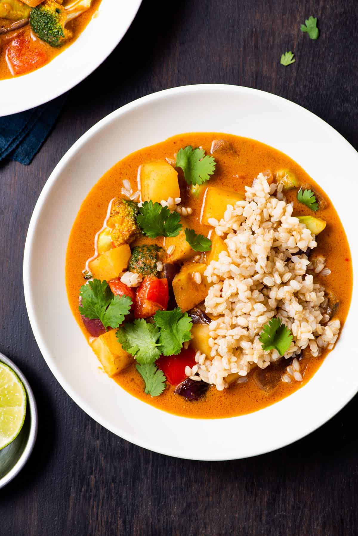 Close-up of massaman vegetable curry with brown rice and basil