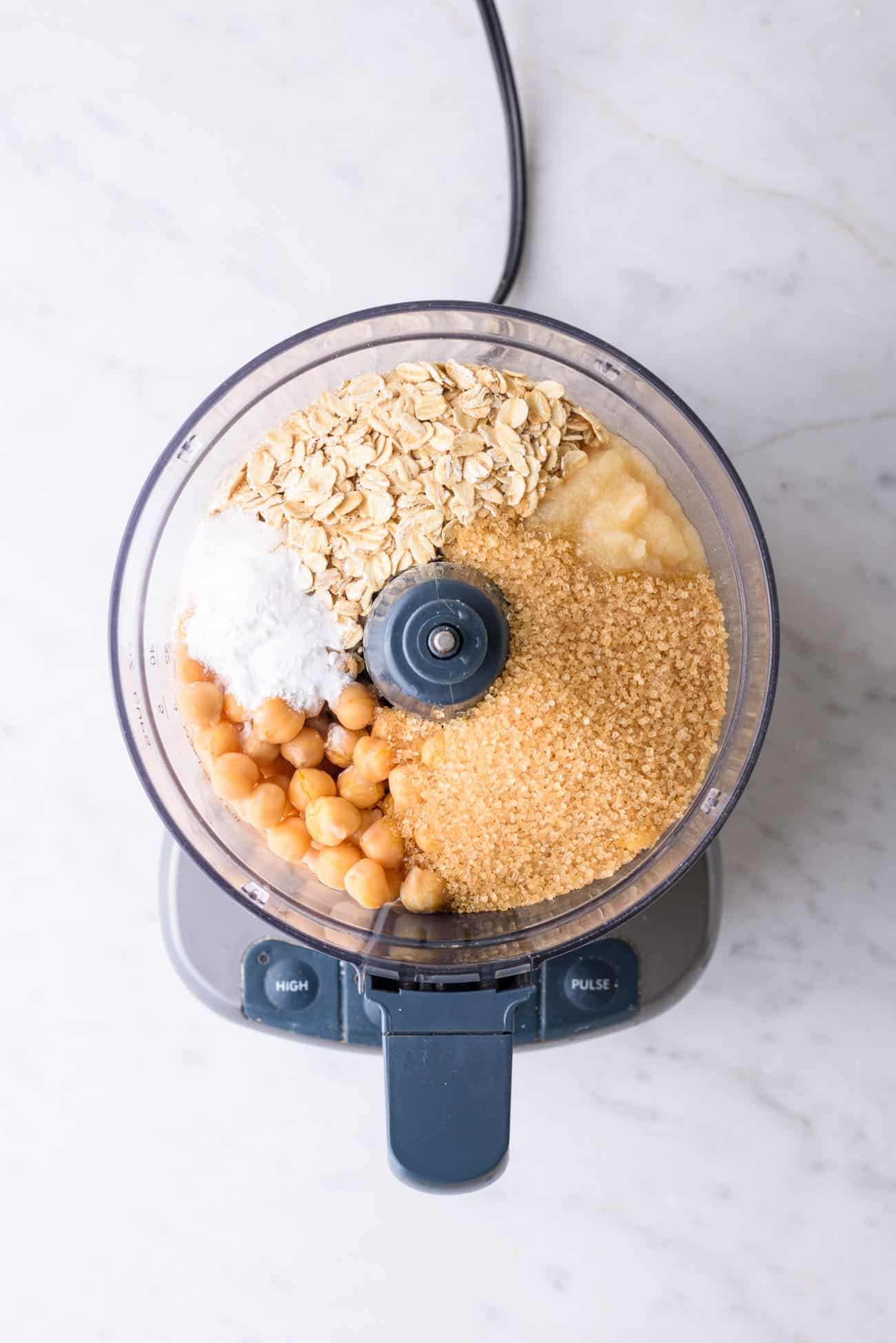 Ingredients to make a vegan chickpea chocolate chip cookie cake in a food processor