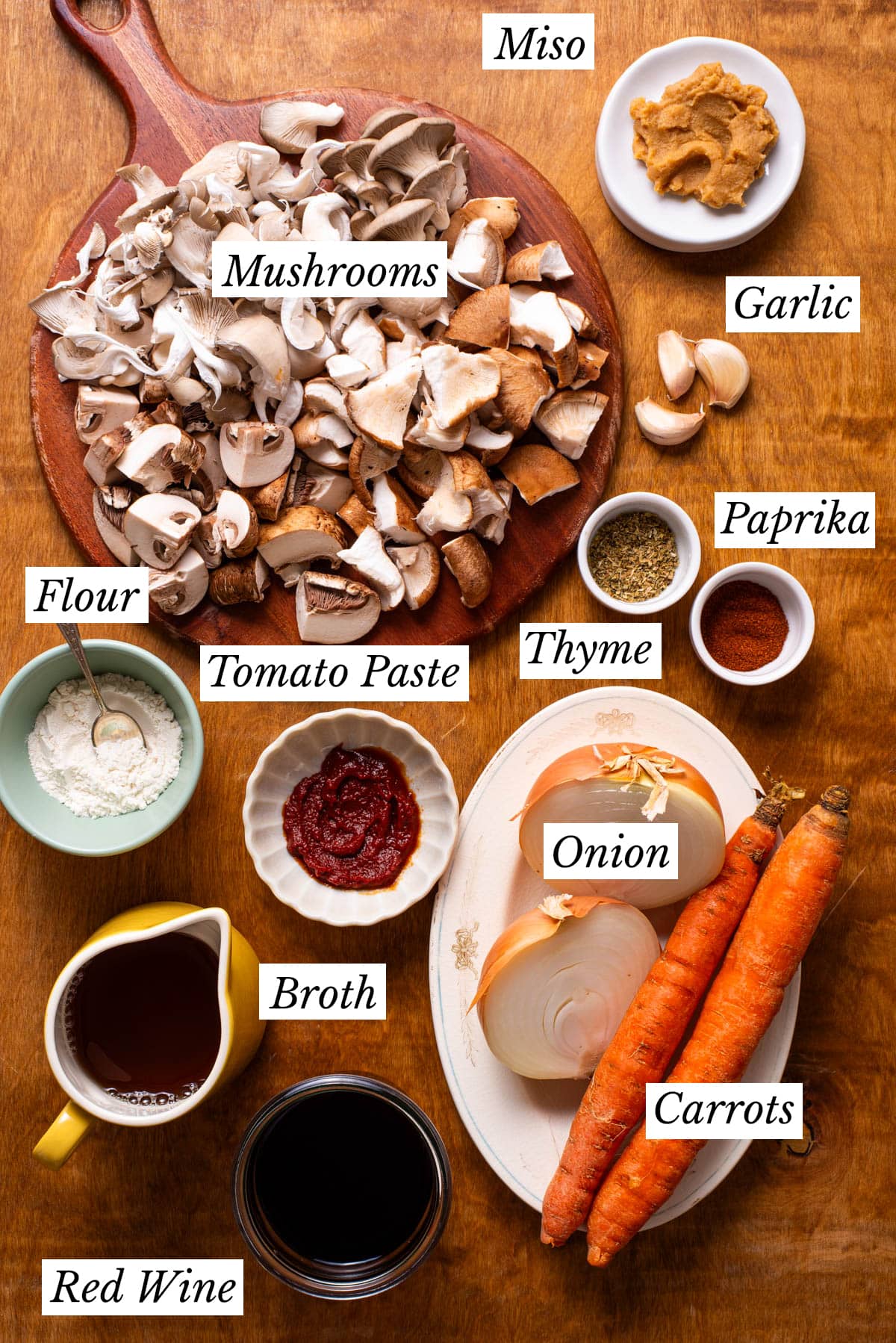 Ingredients to make mushroom bourguignon gathered on a wooden table.
