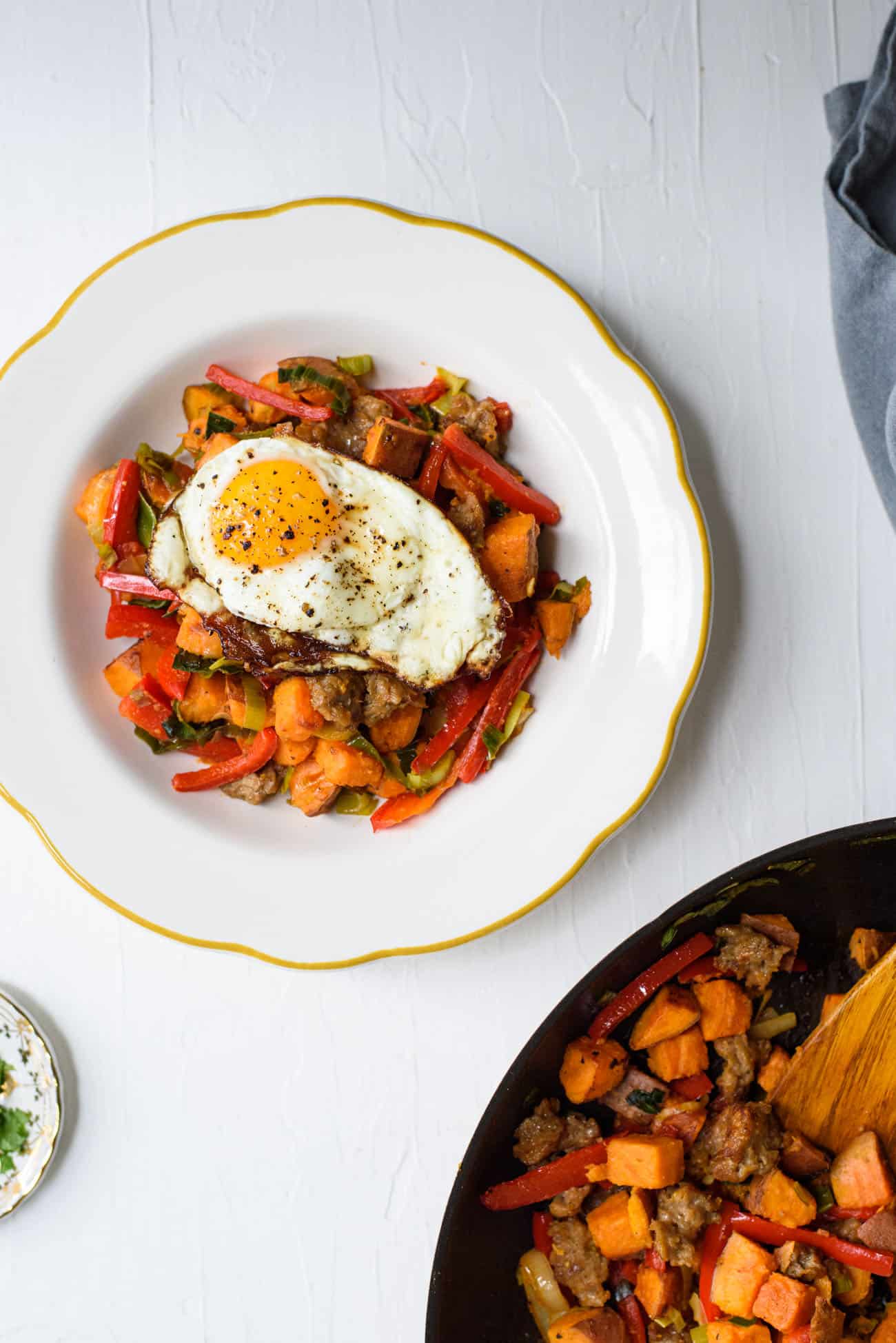 Sweet potato breakfast hash in a white bowl topped with a fried egg