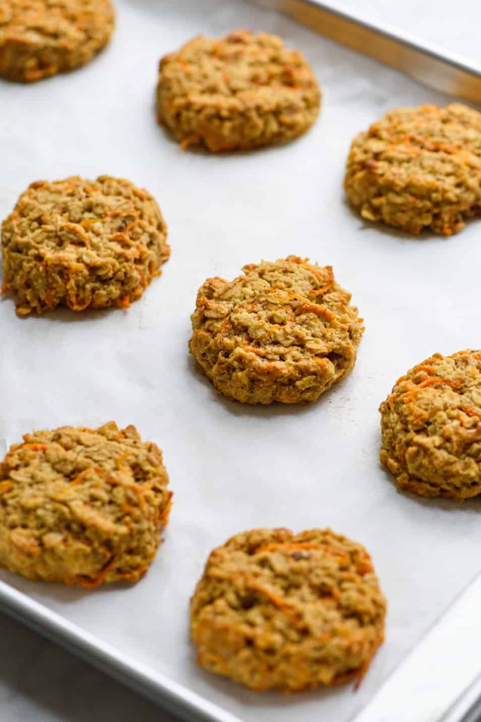 Vegan carrot oatmeal cookies on a baking sheet with parchment paper