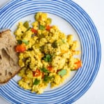 Mexican tofu scramble on a blue-rimmed plate with a piece of sourdough toast