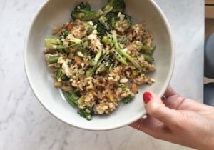 Woman's hand holding a bowl of veggie fried rice