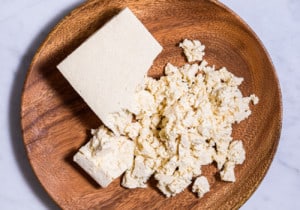 Extra-firm uncooked tofu crumbled on a wooden plate