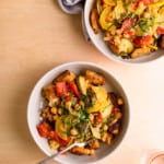 Two bowls of warm panzanella salad on a wooden table