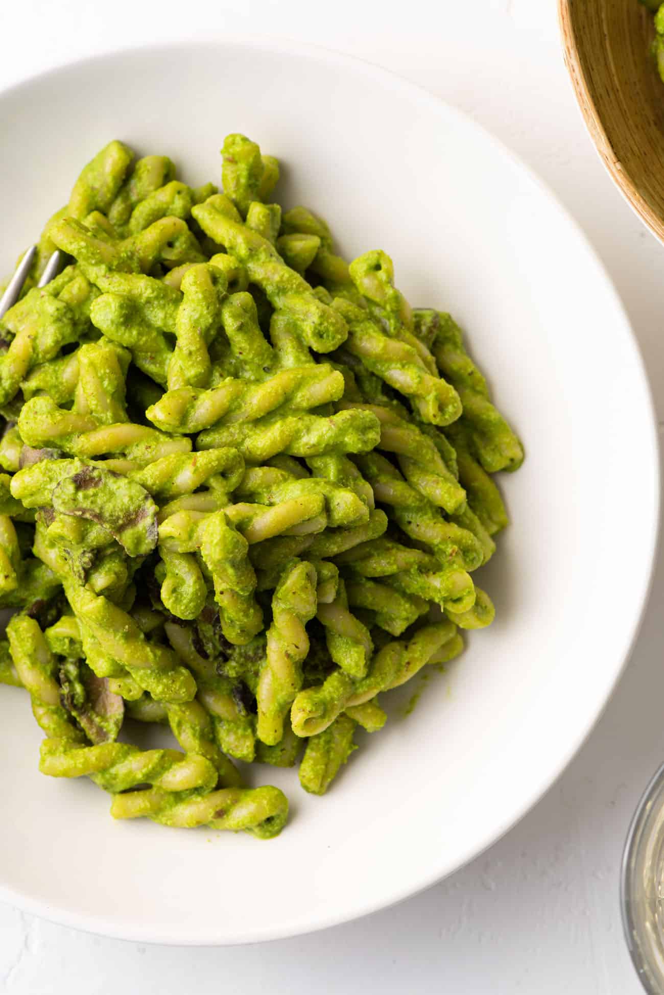 Gemelli with creamy basil spinach pesto in a white bowl.