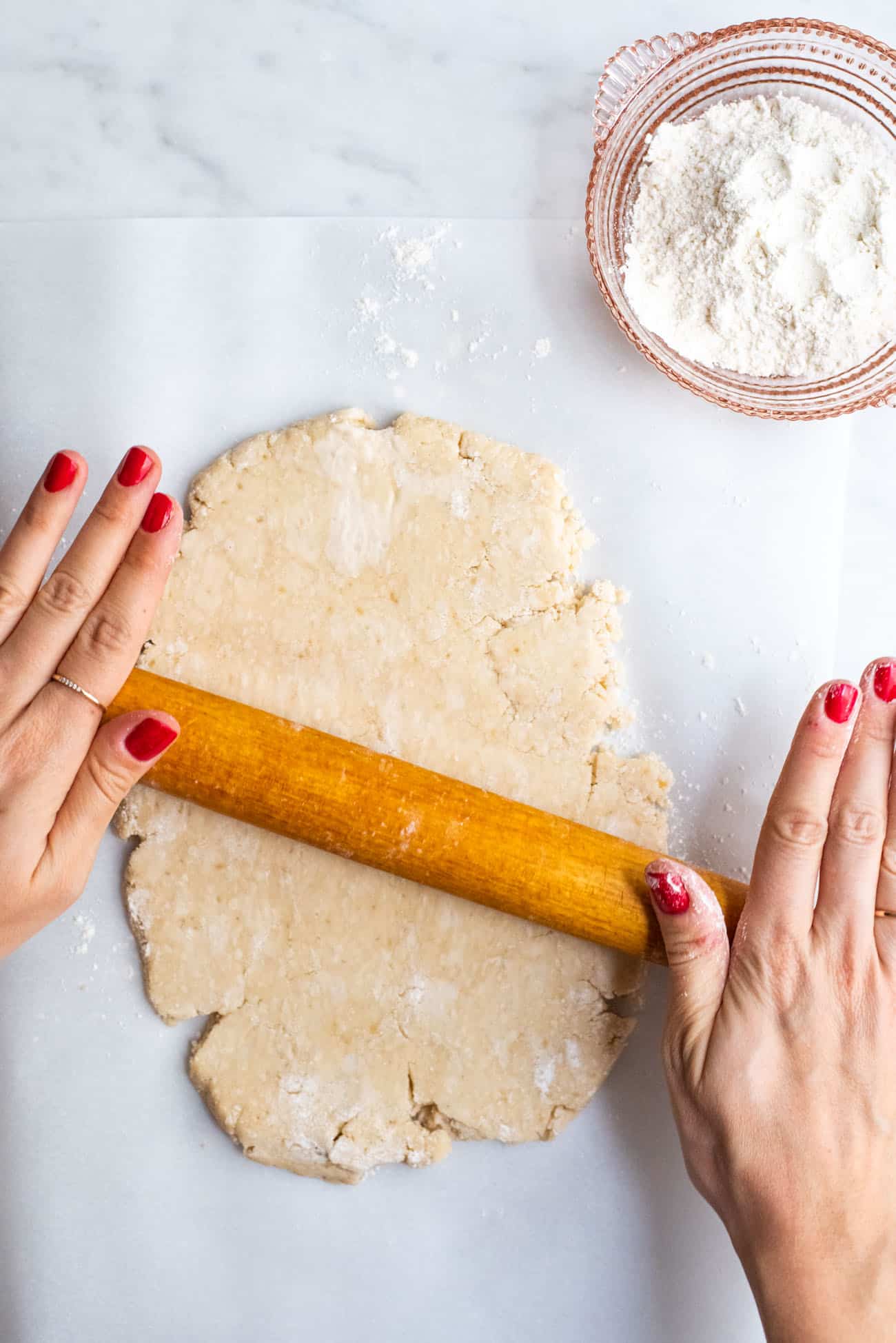 Woman's hands rolling out tart dough.