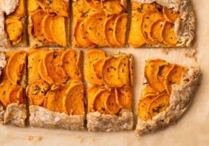 Rectangular vegan sweet potato galette with cashew ricotta on brown parchment paper cut into slices