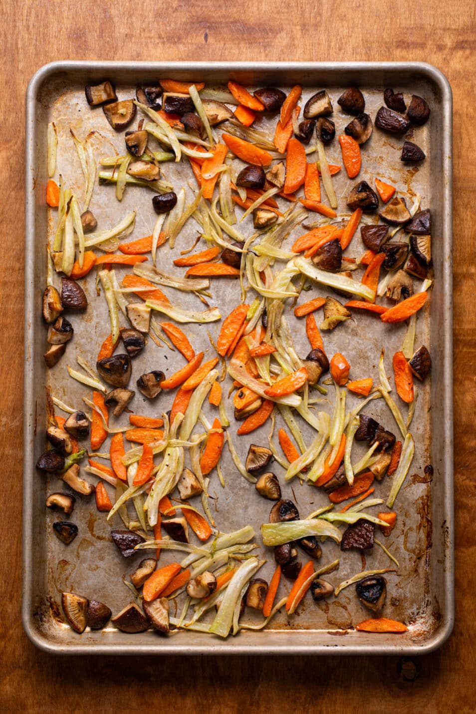 Roasted carrots, fennel, and mushrooms on a baking sheet.