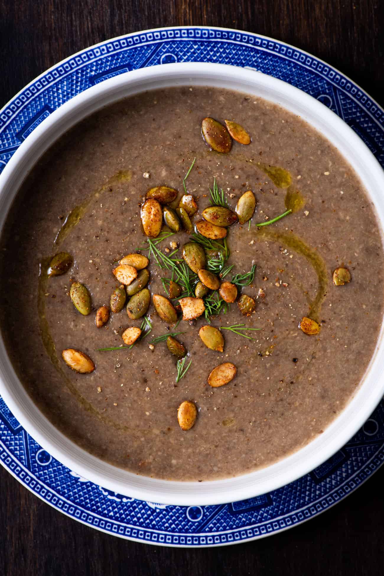 A bowl of creamy vegan mushroom soup topped with spiced pepitas.