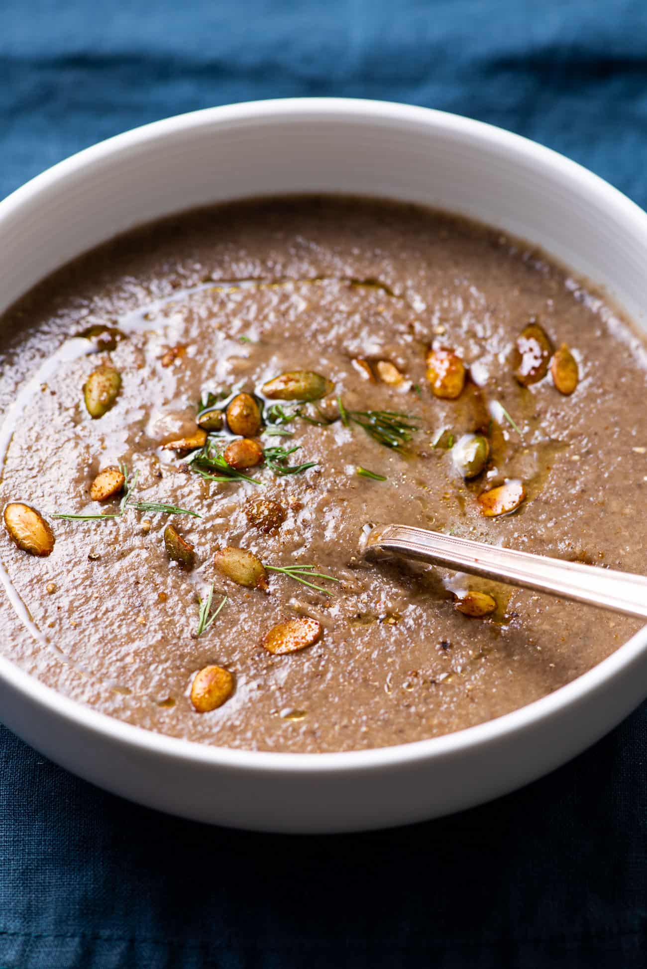 Vegan creamy mushroom soup topped with toasted pumpkin seeds and dill