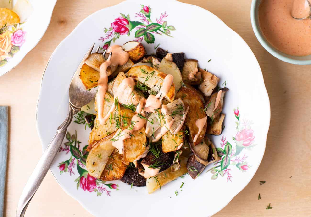 Russian fried potatoes with shiitake mushrooms and dill, on a floral plate, on a wooden table