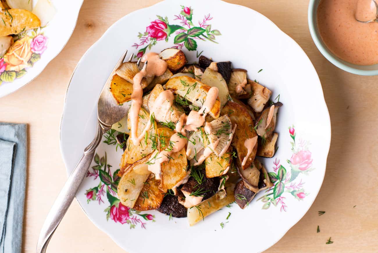 Russian fried potatoes with shiitake mushrooms and dill, on a floral plate, on a wooden table