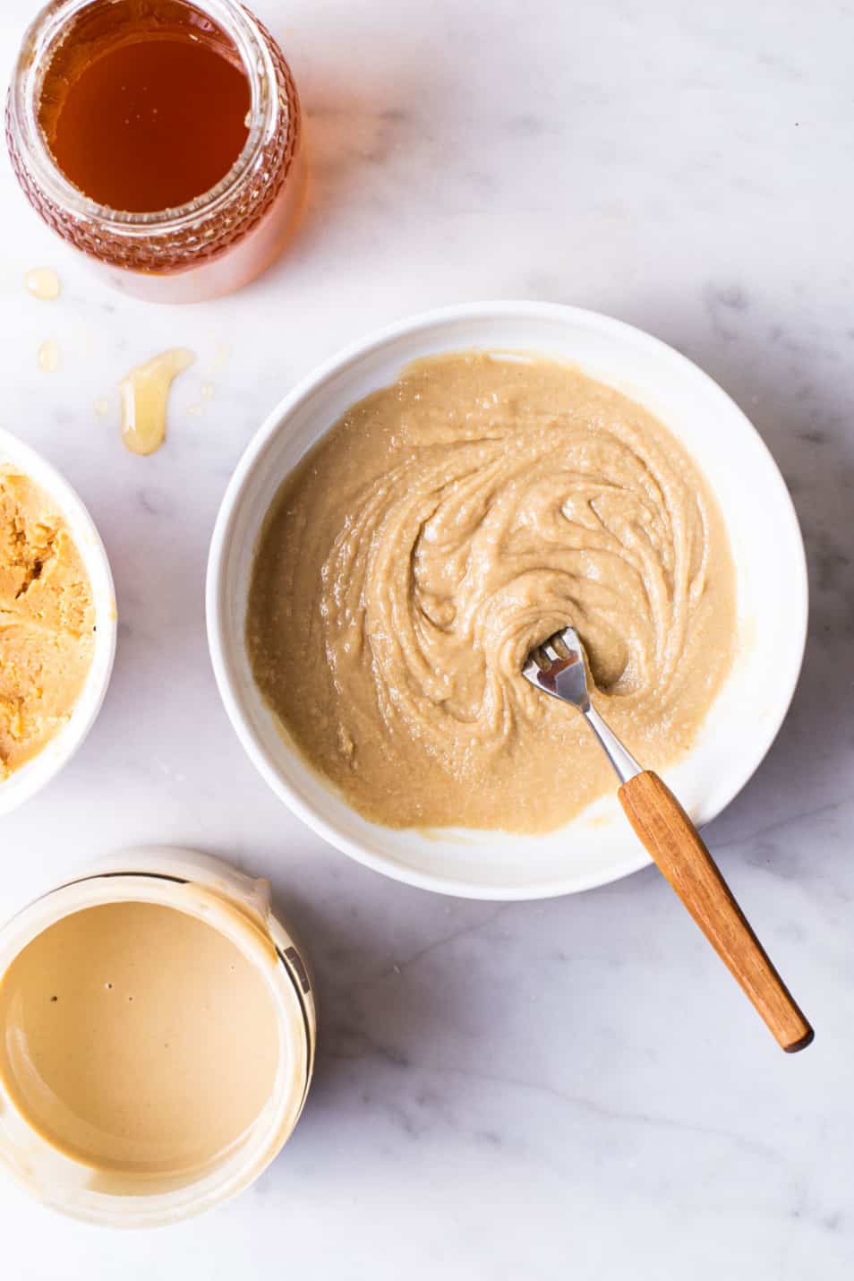 Tahini, miso and honey mixture in a white bowl with a fork