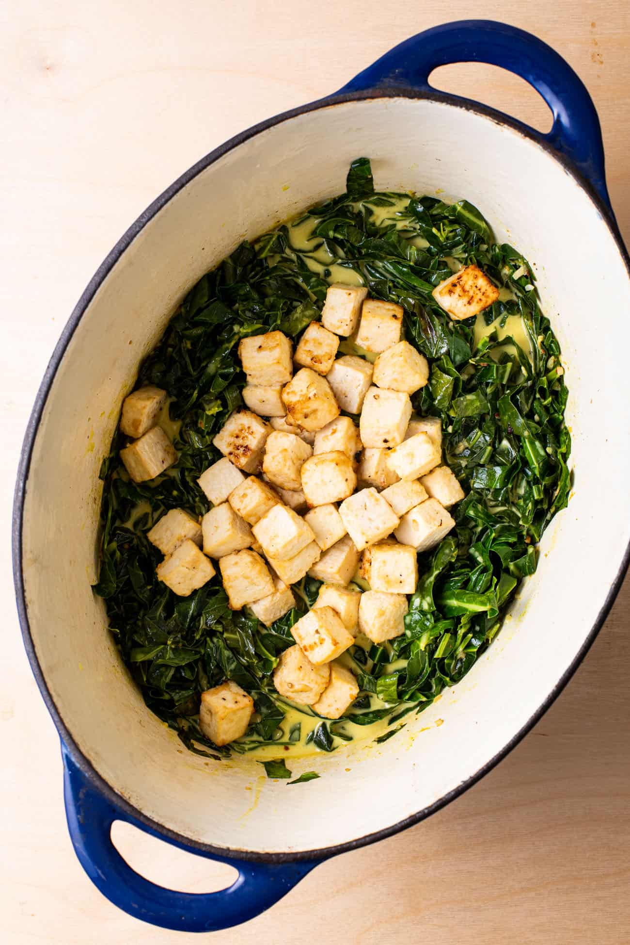 Curried collard greens in a Dutch oven with marinated tofu