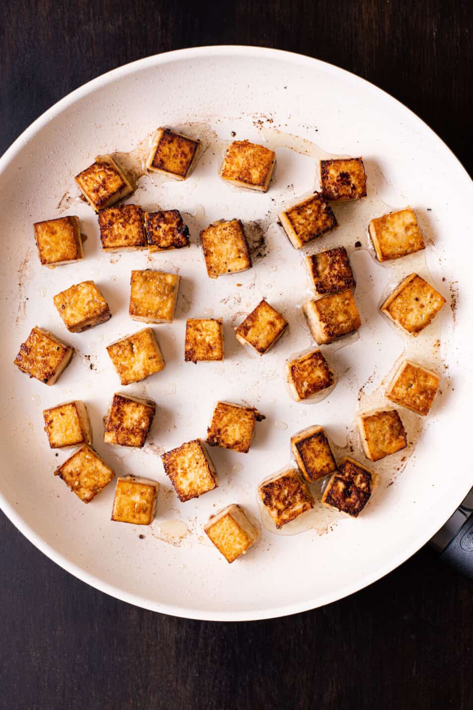 Cubes of pan-fried tofu in a non-stick skillet.