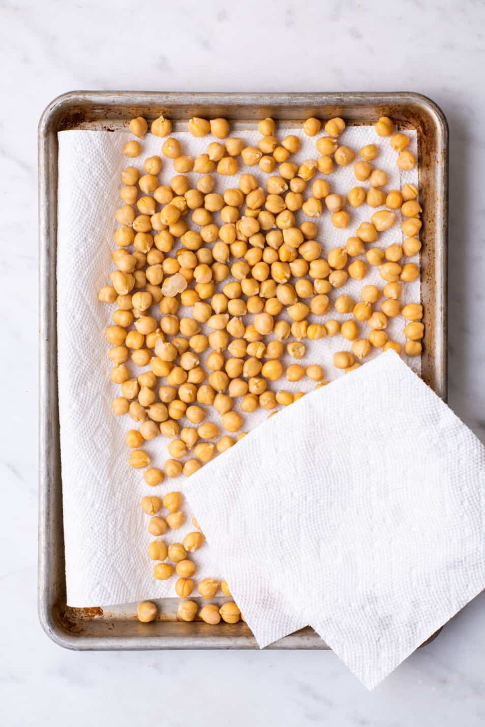 Patting chickpeas dry with paper towels.