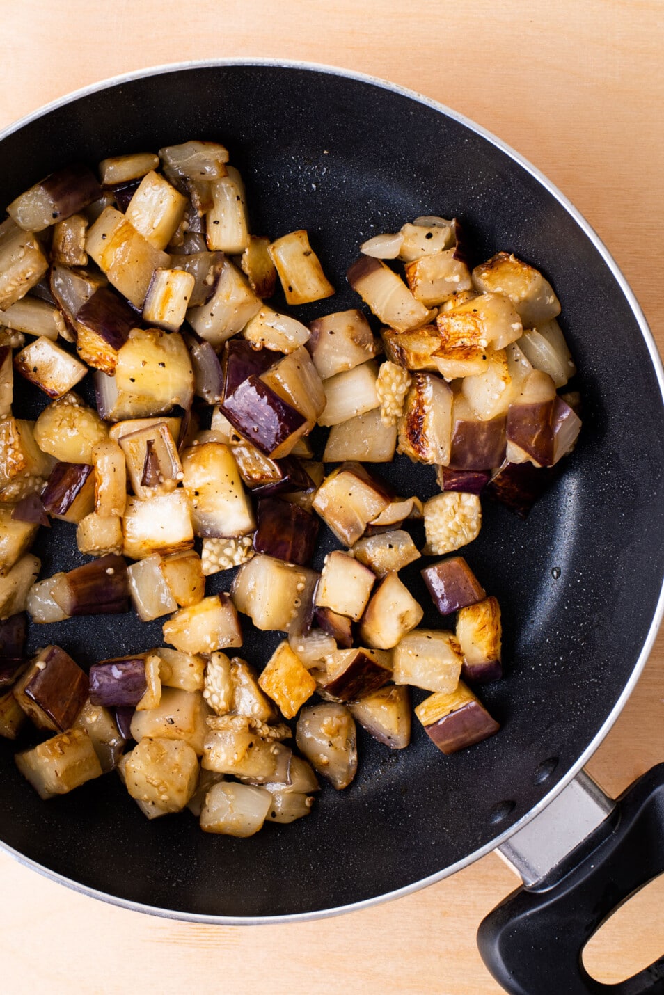 Cubed sauteed eggplant in a pan.