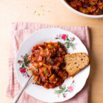 Tomato eggplant stew in a vintage bowl with a slice of bread.