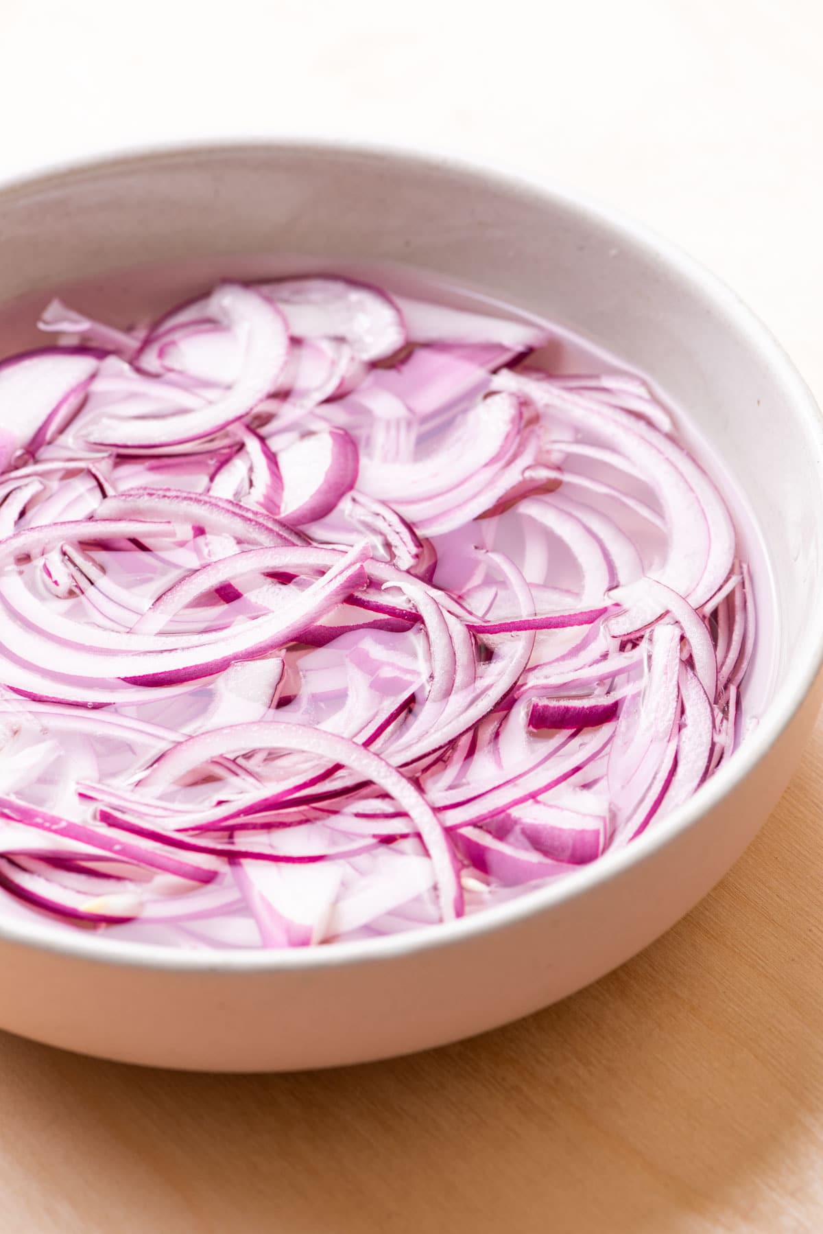 Red onions pickling in vinegar in a bowl.