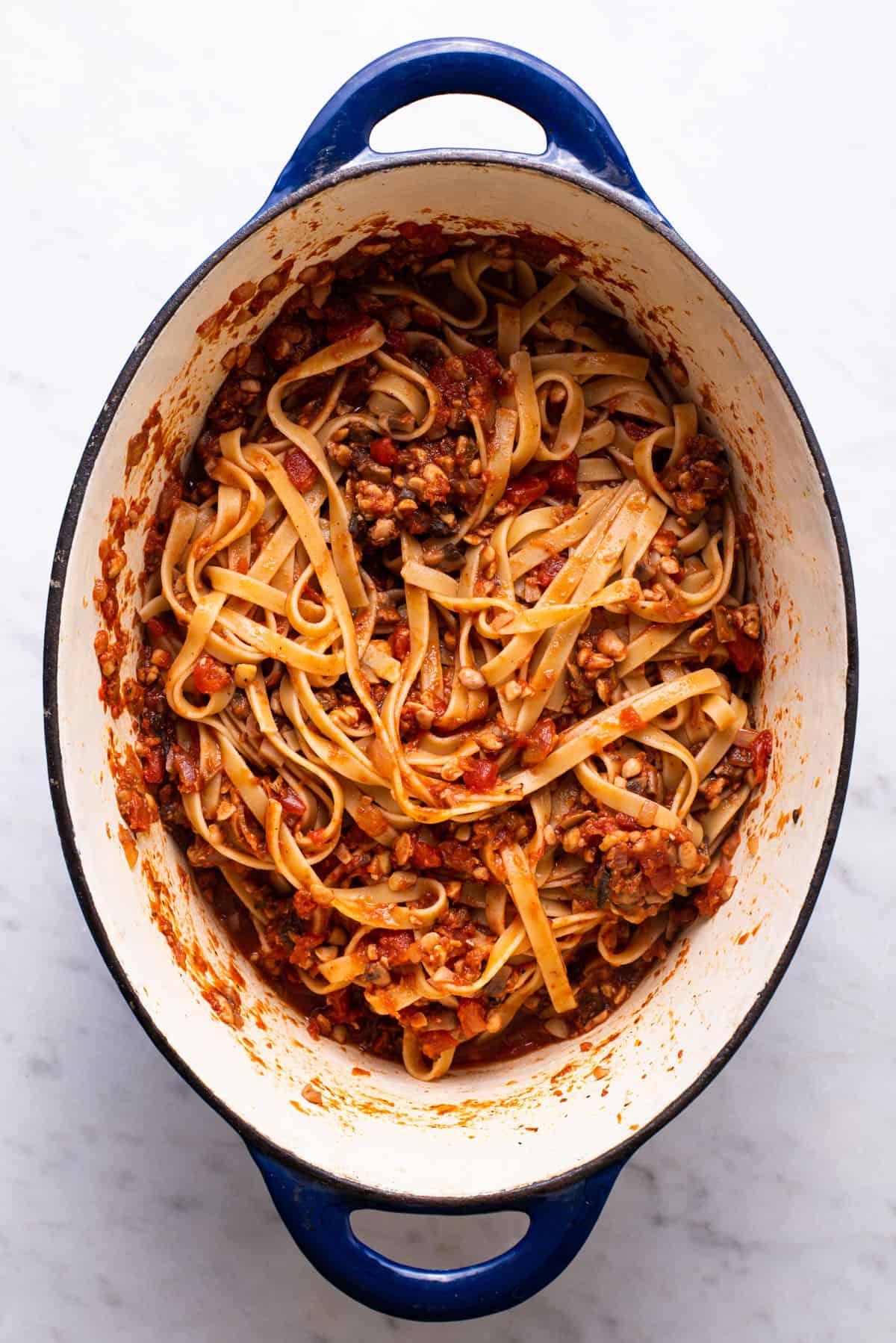 Fettuccine with vegan bolognese sauce in a blue Dutch oven.