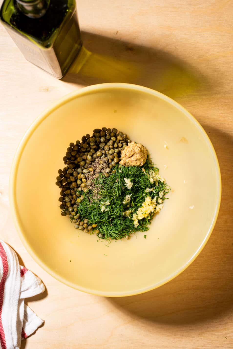 Capers, mustard, garlic, and dill in a large bowl.