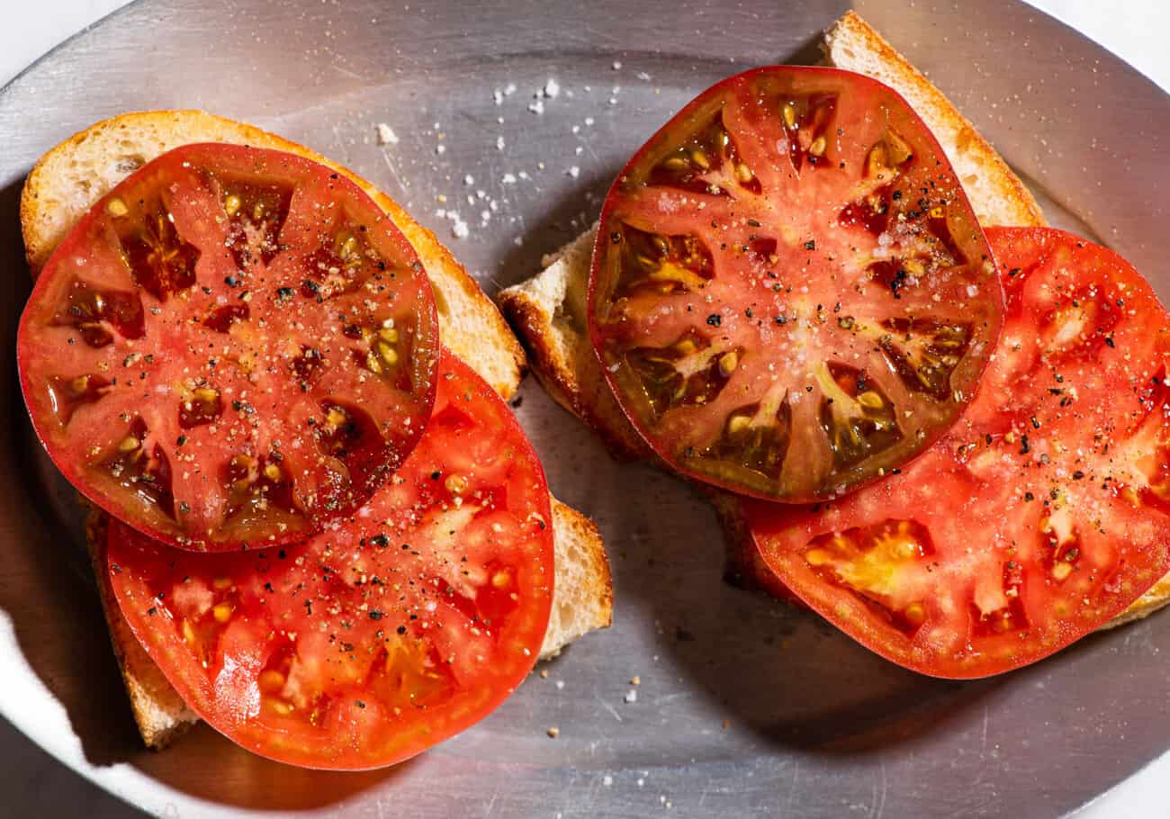 2 pieces of heirloom tomato toast on a sizzle plate.