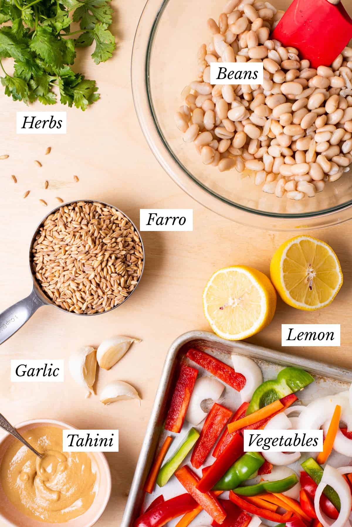 Ingredients gathered to make meal prep farro bowls on a wooden table.