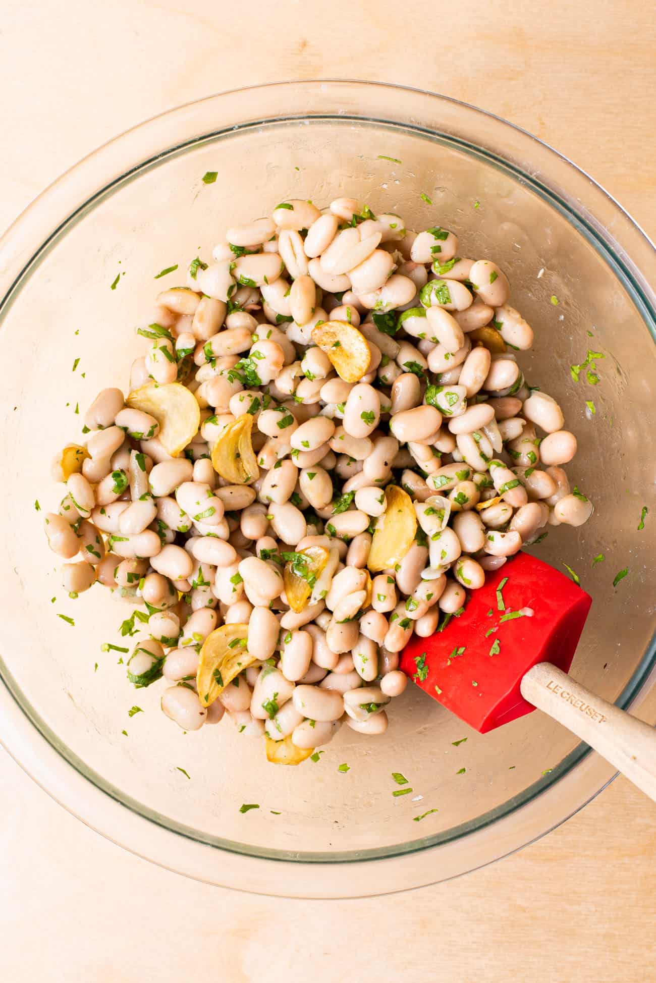 Garlicky white bean salad with cilantro in a glass bowl.